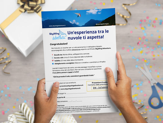 Mockup con mani che tengono il finto voucher ironico di Augurino per volo in deltaplano, per persone che soffrono di vertigini.