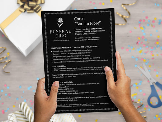 Mockup ironico di augurino del finto voucher per il corso per diventare esperti di arte floreale funeraria tenuto tra le mani